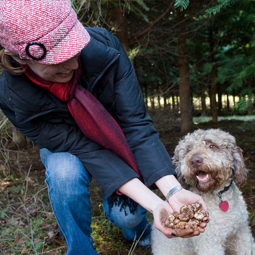 A woman posing with her dog, a bounty of truffles displayed in her hands